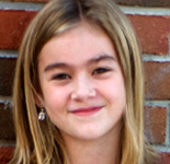 little girl standing against brick wall