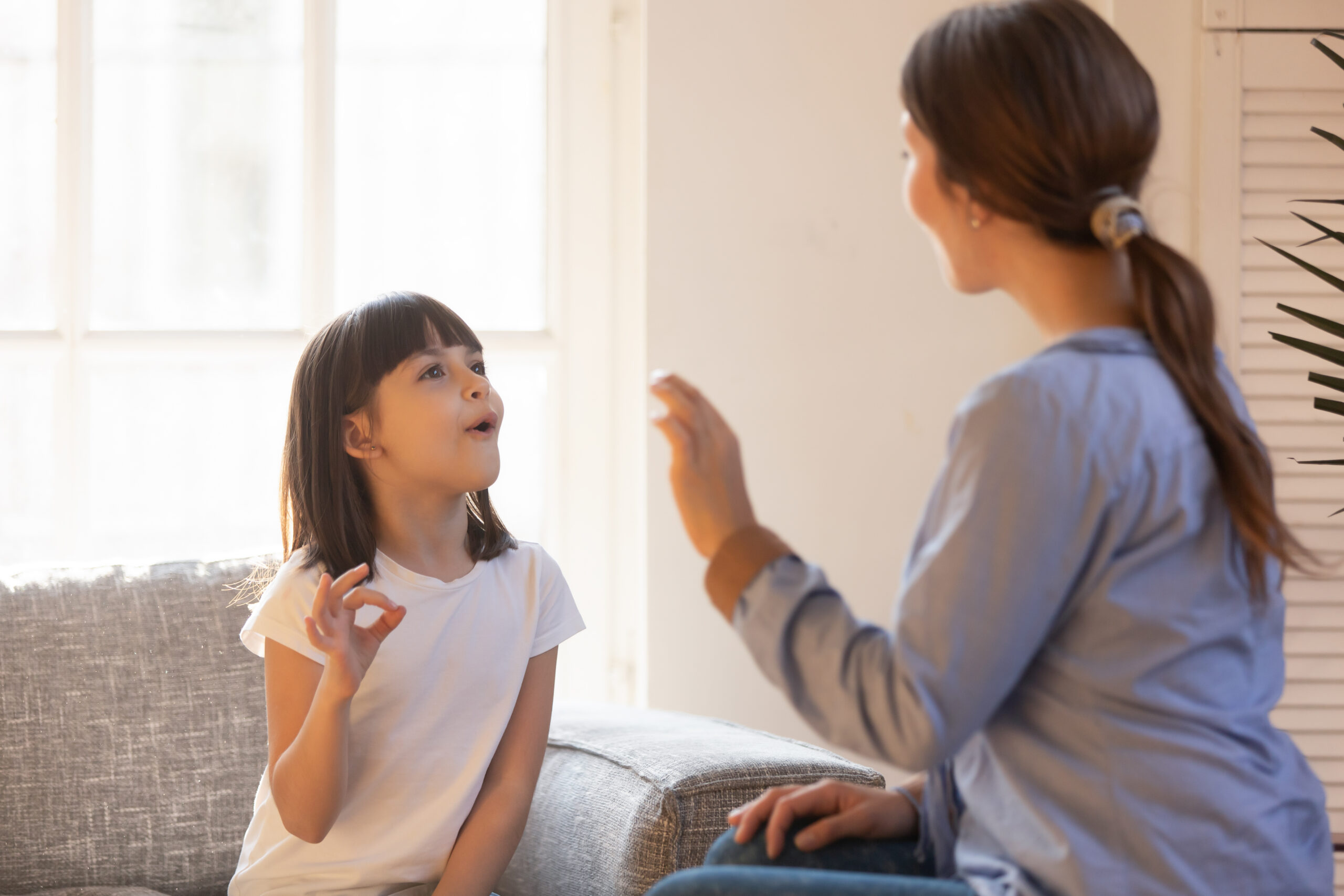 Mom and daughter practice sign language at home